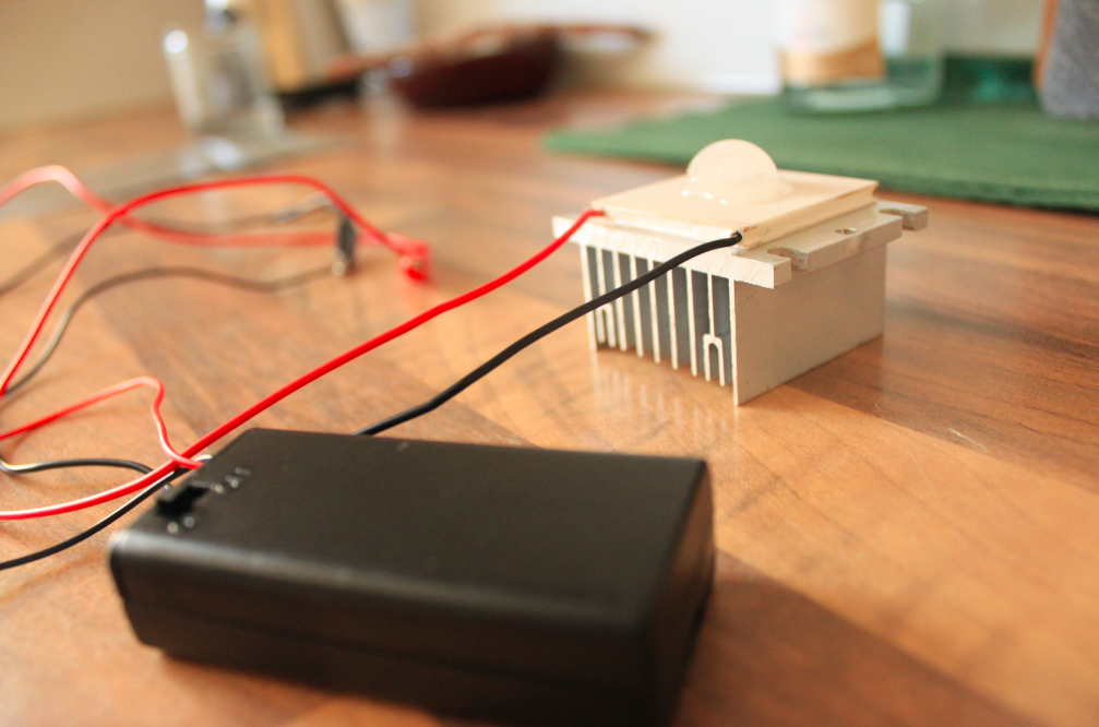 Thermoelectric cooler experiment using Peltier module connected to a 3V battery; a small ice cube placed on the surface of the module slowly melts.